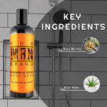 Business As Usual Body Wash in a dark bottle with a bright orange label, featuring bold black lettering and a black cap.